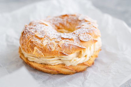 French traditional cake Paris Brest with praline cream, powdered sugar and almond petals on top on a...