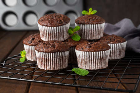 Chocolate muffins or cupcakes with chocolate drops on a dark wooden background with fresh berries and mint. Copy spaceの写真素材