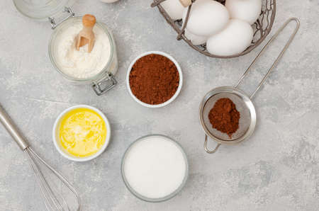 Ingredients for making chocolate sponge cake for roll. Eggs, flour, butter, sugar, cocoa on a gray concrete background. Recipe step by step. Top viewの写真素材