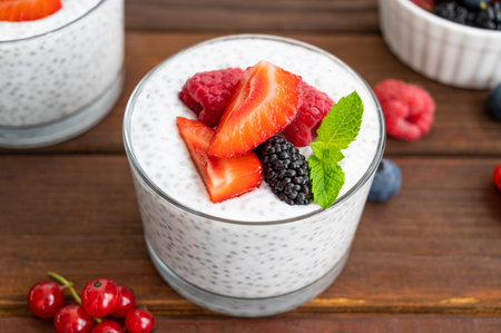 Vanilla chia pudding with fresh berries and honey in a glass on a dark wooden background. Superfoods concept. Copy spaceの写真素材