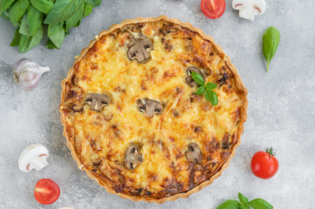 Quiche with mushrooms and chicken in a creamy filling on a gray concrete background. Copy space