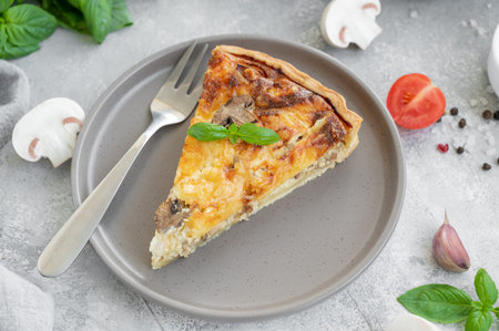 Quiche with mushrooms and chicken in a creamy filling on a gray concrete background. Copy space