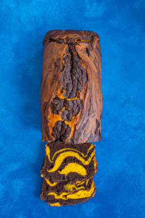 Pumpkin chocolate marble cake or bread on a blue concrete background. Dessert for Thanksgiving or...