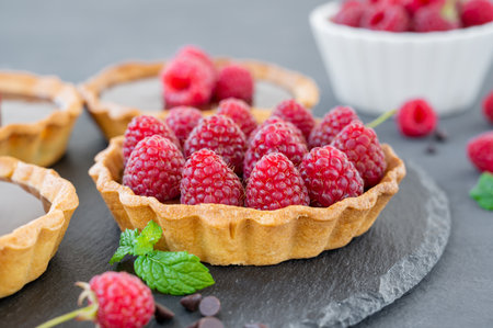 Delicious tart with chocolate cream and fresh raspberry on a gray background. summer dessert. copy spaceの写真素材