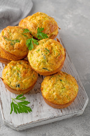 Homemade zucchini muffins with cheese, garlic and herbs on a plate on a gray concrete background. Vegetarian dish. copy spaceの写真素材