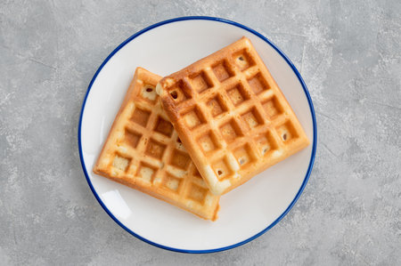 Waffles with banana, whipped cream and salty caramel on a gray concrete backgroundの写真素材