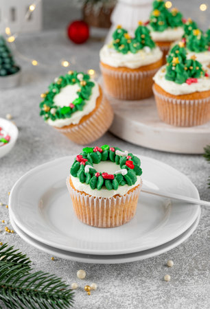 Christmas tree and wreath shaped cupcakes with candy sprinkles on top. Christmas dessert on a light concrete backgroundの写真素材