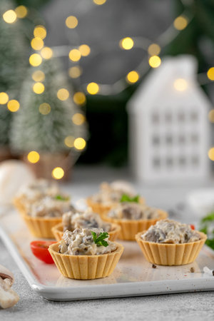 Christmas food. Mini tartlets with mushrooms in a cream sauce, with cheese, garlic and herbs on a ceramic board on a gray concrete backgroundの写真素材
