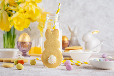 Easter Bunnies cookies with a bottle of milk on a concrete background with flowers. Easter food...