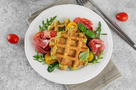 Spinach waffles with tomatoes, arugula and prosciutto on a white plate with a cup of coffee. Healthy breakfast. Top view.の写真素材