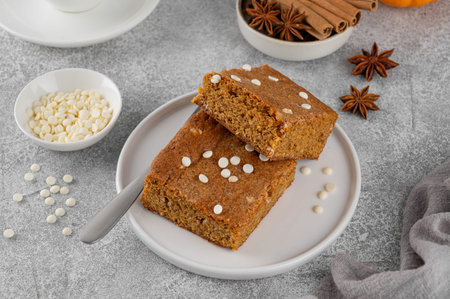 Pumpkin brown butter blondies or pumpkin cake with white chocolate drops and spices on a gray...