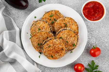 Baked garlic crispy eggplant with tomato sauce on a plate. Vegetarian food. Selective focus, top viewの写真素材