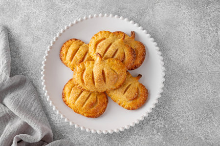 Pumpkin mini pies or hand pies with glass of coffee on a stone background. Traditional autumn...