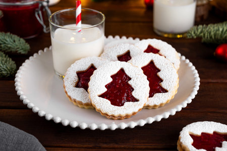 Linzer cookies. Traditional Christmas Austrian cookies with red raspberry jam sprinkled with powdered sugar on top on a plate on a dark wooden background. Copy space.の写真素材
