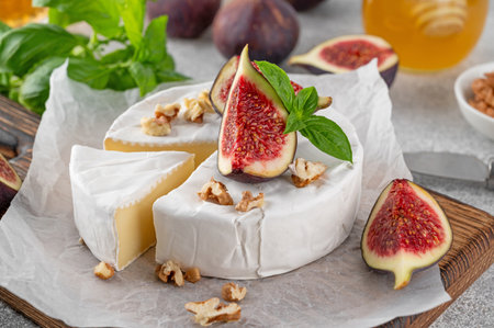 Camembert, bree cheese, walnuts, fresh figs and honey on a cutting board on a concrete background. Charcuterie Board. Top view.の写真素材