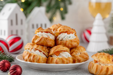 Savory profiteroles with smoked salmon, cream cheese and dill on a plate on a concrete background. Appetizer for Christmas and New Year. Selective focus, copy spaceの写真素材