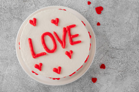 Vanilla strawberry cake with small red hearts for Valentine's day on a white plate on a gray concrete background.の写真素材