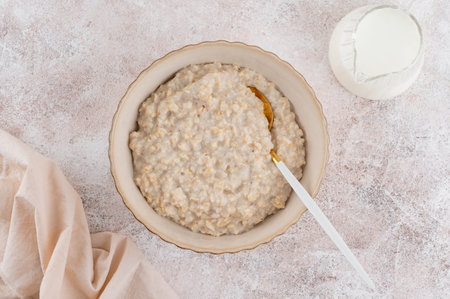 Oatmeal with milk in a bowl on a concrete background. Healthy breakfast. Top view