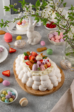Easter egg-shaped Pavlova cake with whipped cream, topped with fresh berries and assorted sweets on...