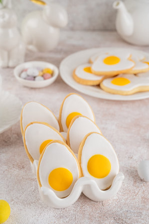 Easter cookies in the form of eggs with sugar glaze on a stone background. Food idea for kids. Top...