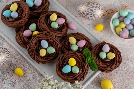 Easter chocolate nest cookies with chocolate cream and colorful candy eggs on a white ceramic board....