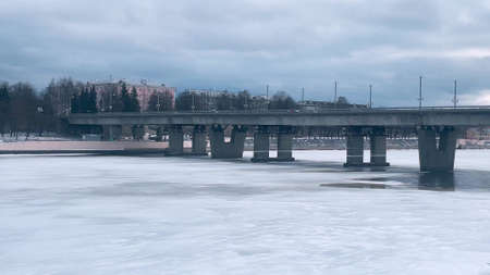 View of the bridge, located in the city above the river, on which cars are driving, people are walking in winterの写真素材