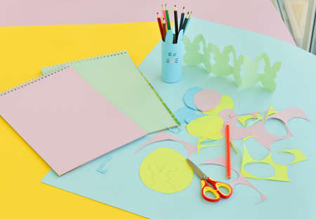 Flat lay diy paper with Easter bunnies made of paper with your own hands and colored egg templates, simple crafts and applications for preschoolers.の写真素材