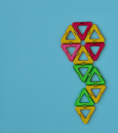 Childrens magnetic constructor. A flower laid out of multicolored details of triangles, layout, a...