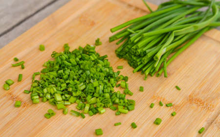 Fresh green onions on a cutting wooden board.の写真素材