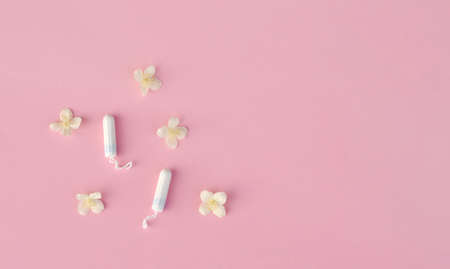 Women's and gynecological health care. menstrual cycle. Hygiene care during critical days. Tampon woman Clean lie on a pink background among white flowers, safe Menstruation, means of protection.の写真素材
