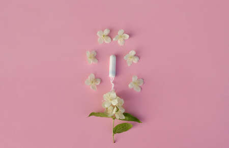 Women's and gynecological health care. menstrual cycle. Hygiene care during critical days. Tampon woman Clean lie on a pink background among white flowers, safe Menstruation, means of protection.の写真素材