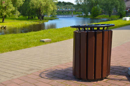 Brown wooden trash can on the street on the riverbank in the park. Garbage container outside.の写真素材