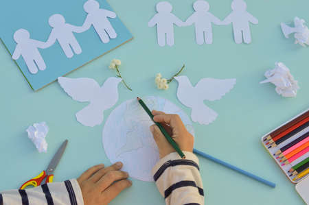 A close-up of the hands of an Indian child who makes a postcard for the International Day of peace, crafts with his own hands, do it yourself, what to do with children. The concept of the World Peace Day.の写真素材