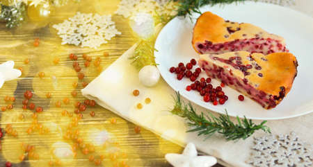 Traditional homemade Christmas cake on a white plate festive dessert with cranberries on the background of Christmas decorationsの写真素材
