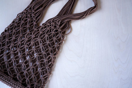 Brown string bag knitted in macrame technique from a knitted cord on a wooden background. Zero waste and plastic free concept. A place for your text, advertising.の写真素材