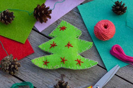 Felt sheets, scissors, thread on wooden table. New year craft ideas for kids. Green felt...