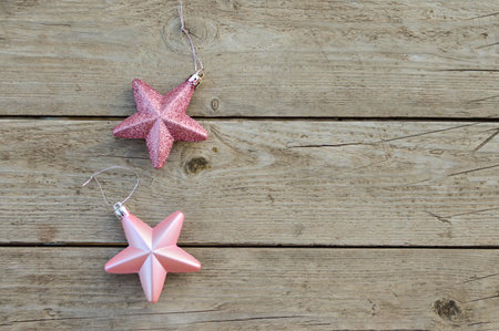 Pink Christmas decorative stars on a rustic wooden background. Waiting for the holiday, a place for...