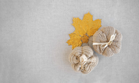Hobby background with handmade knit pumpkins and golden maple leaves. DIY, craft decoration for fall and winter holidays. Flat lay, top viewの写真素材
