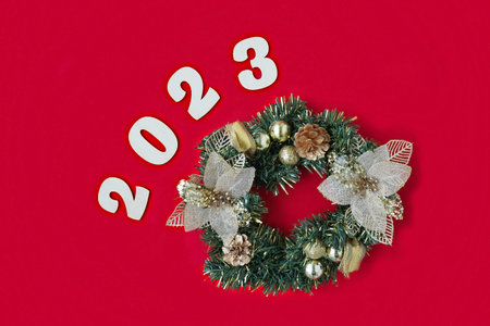 christmas wreath with golden balls, cones and bows on a red background with wooden numbers