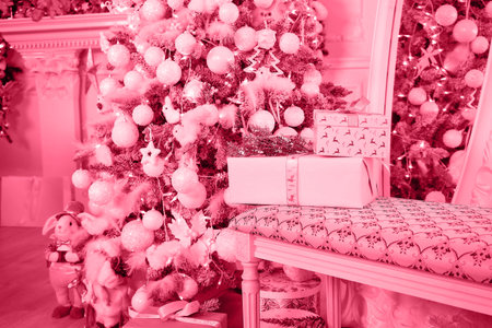 Classic white christmas interior with new year tree decorated. Fireplace with grey chair, clocks on the wall and presents under the tree Tinted imageの写真素材