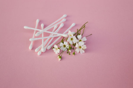 White buds near white flowers on light pink, close up. Skincare product for everyday beauty routine. beauty concept. flat layの写真素材