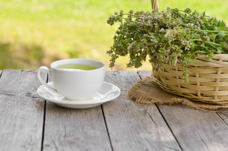Fresh natural green melissa herbal tea in white cup. Organic aromatherapy relaxation medical healthy beverage. Rustic wooden table background. Rustic style natural light.の写真素材