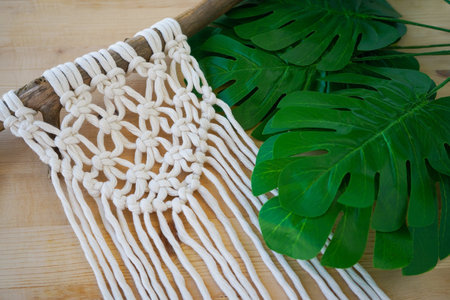 macrame technique for home decor and wedding decoration lying on a wooden table. Beautiful boho macrame wall panel will add a cozy atmosphereの写真素材