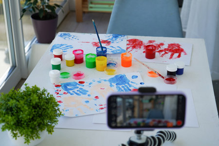 Children bloggers are streaming finger painting. live broadcast, online. Kids have fun and create picture. Palms of different colors. Sensory development and experiencesの写真素材