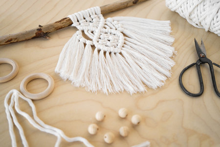 A Hand-Made Macrame Plant Hanger with Wooden Rings in a Beautiful Background Setting the Mood for Creativity.の写真素材