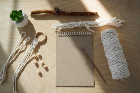 Tools and materials for macrame. Cotton ropes, sticks from the river, grinded by water. Notepad with...