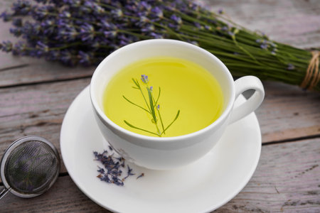 White cup with lavender tea and fresh lavender flowers on an old wooden backgroundの写真素材