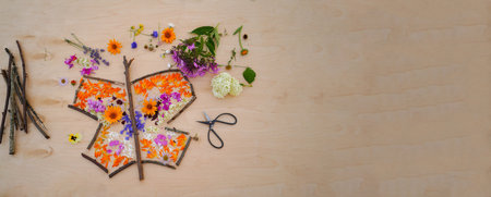 Banner with butterfly made from flowers, easy nature craft for kids. Making fairy landscape, inspiration, imagination, sensory perception. easy nature craft for kidsの写真素材