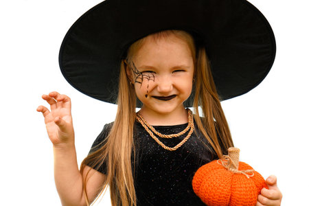 Portrait of winsome little witch smiling girl wearing a wizard hat and dressed in stylish carnival...