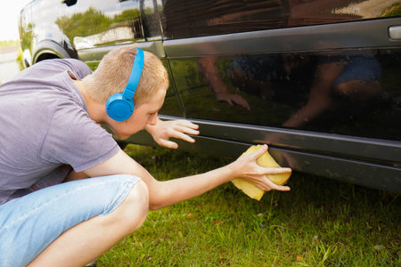 Teenager Boy Washing and Cleaning car in front of his Houseの写真素材